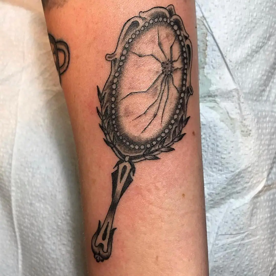 Intricate cracked mirror tattoo with vintage flair