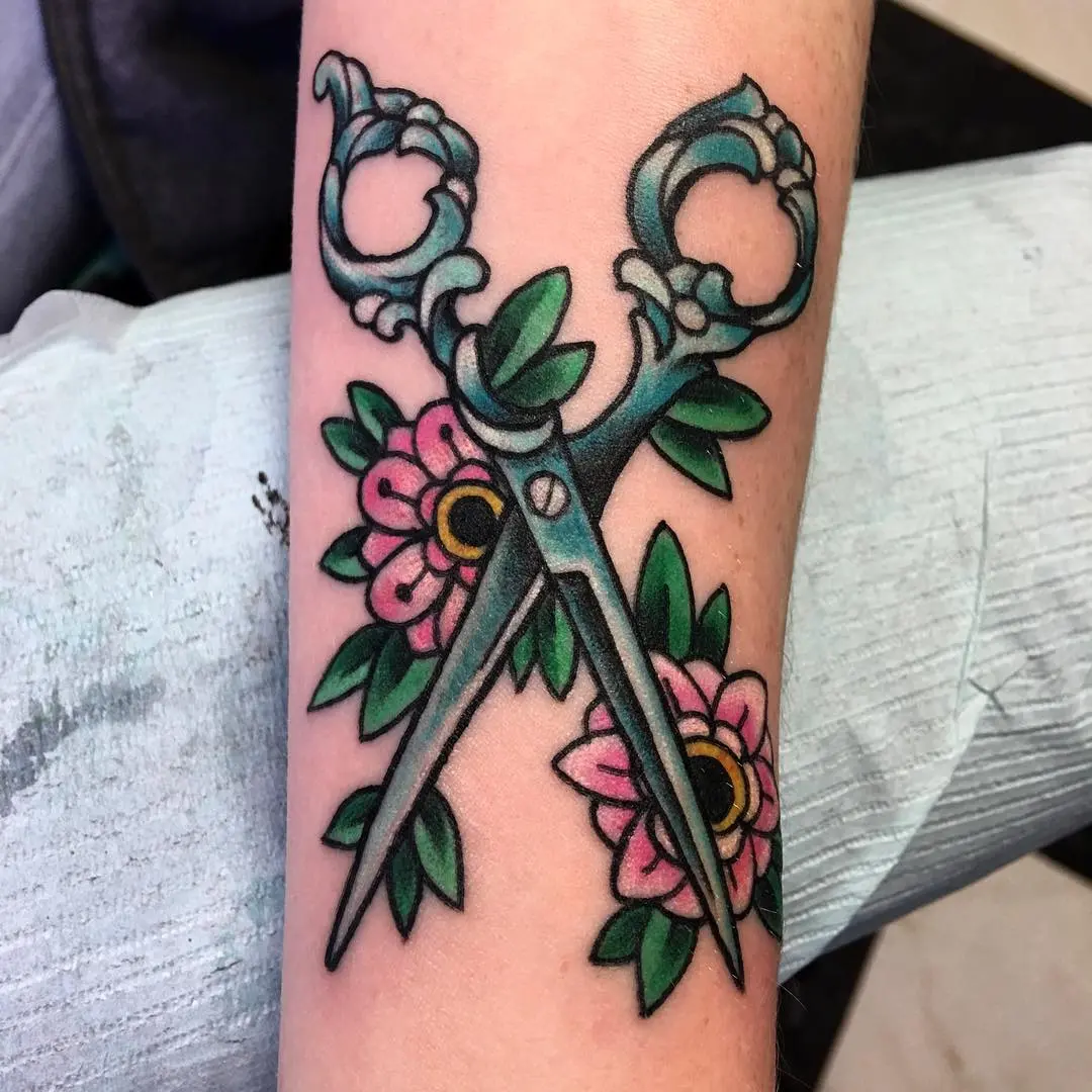 Creatively designed tattoo featuring scissors and flowers