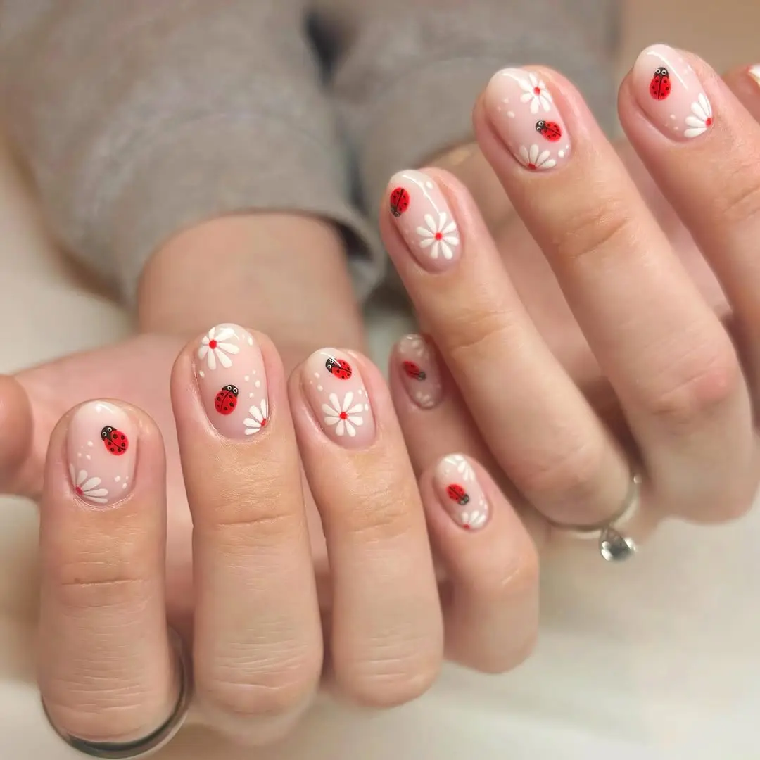 Charming ladybug nail art with floral accents