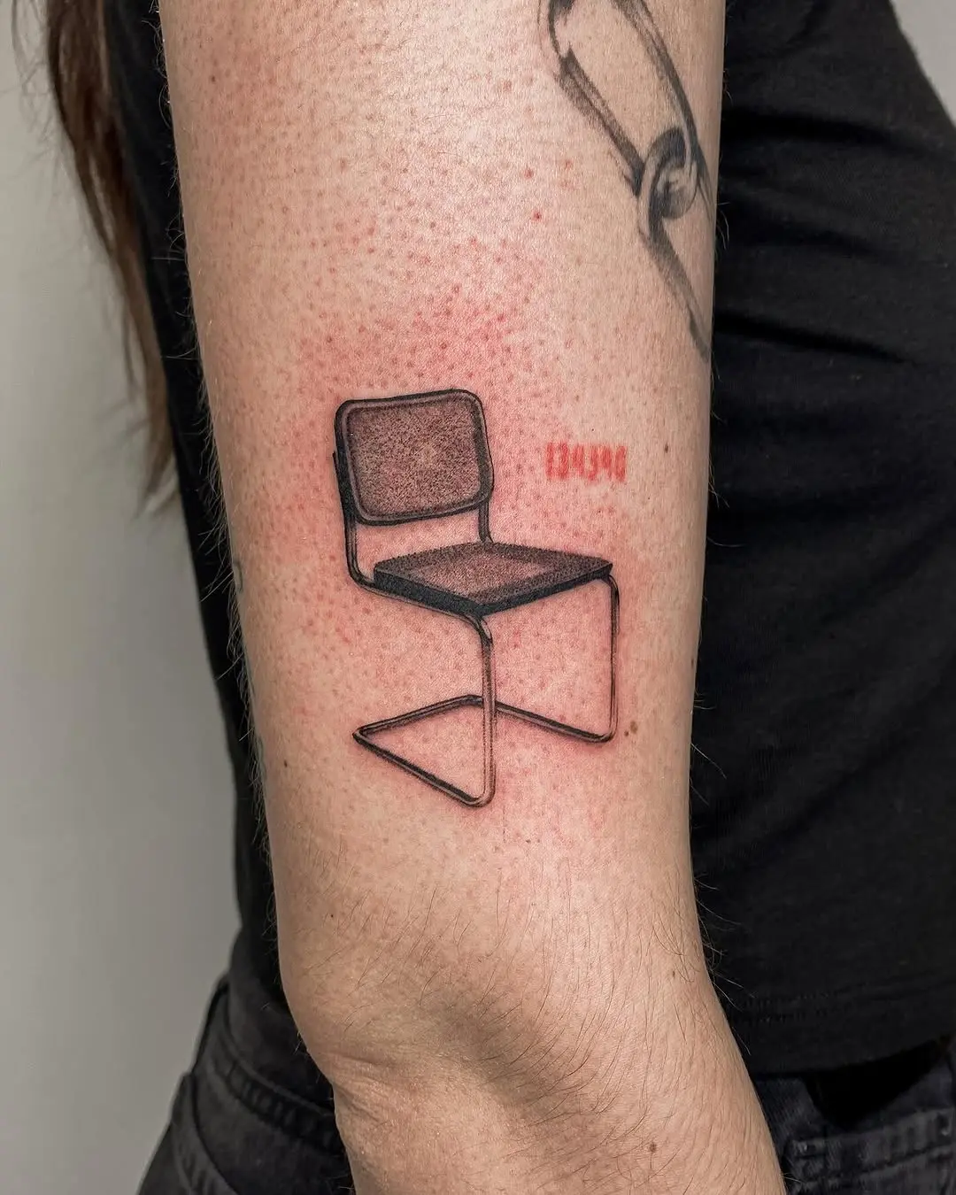 Minimalist chair design tattoo on forearm