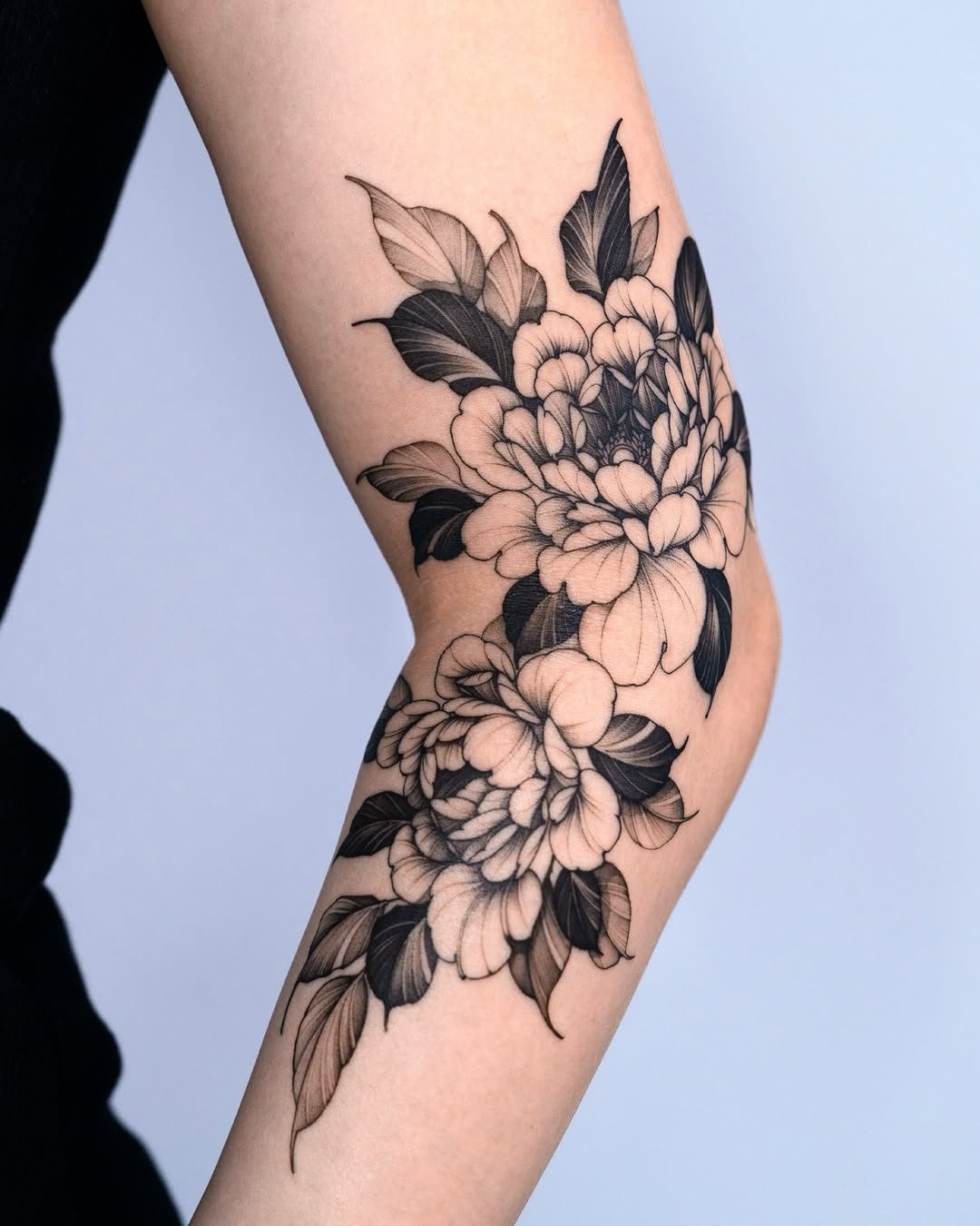 Elegant blackwork peony tattoo on elbow