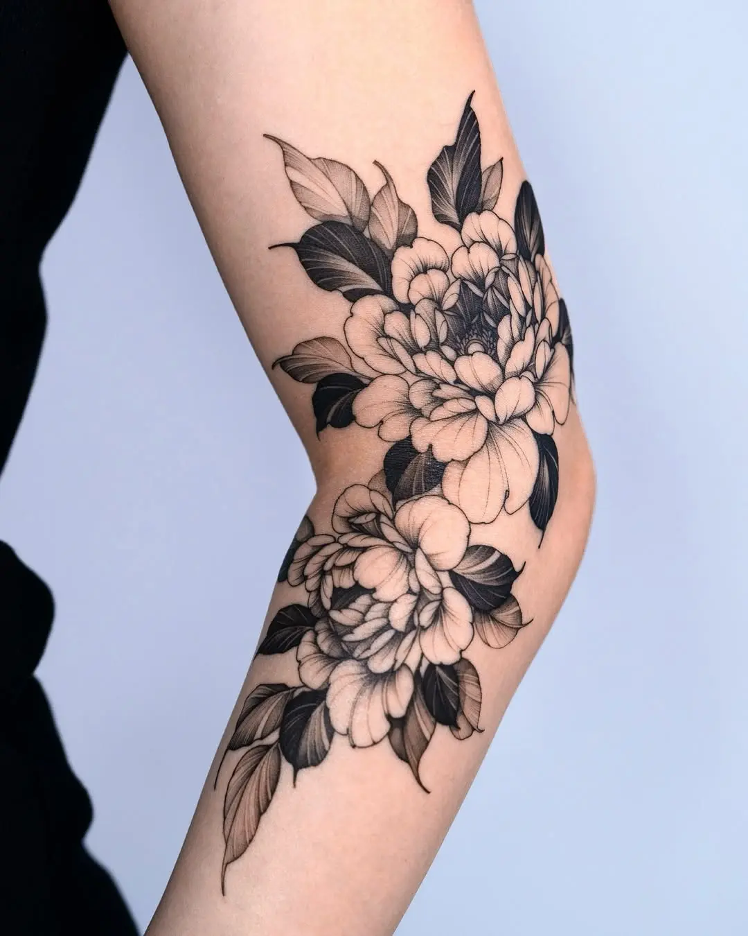 Elegant blackwork peony tattoo on elbow