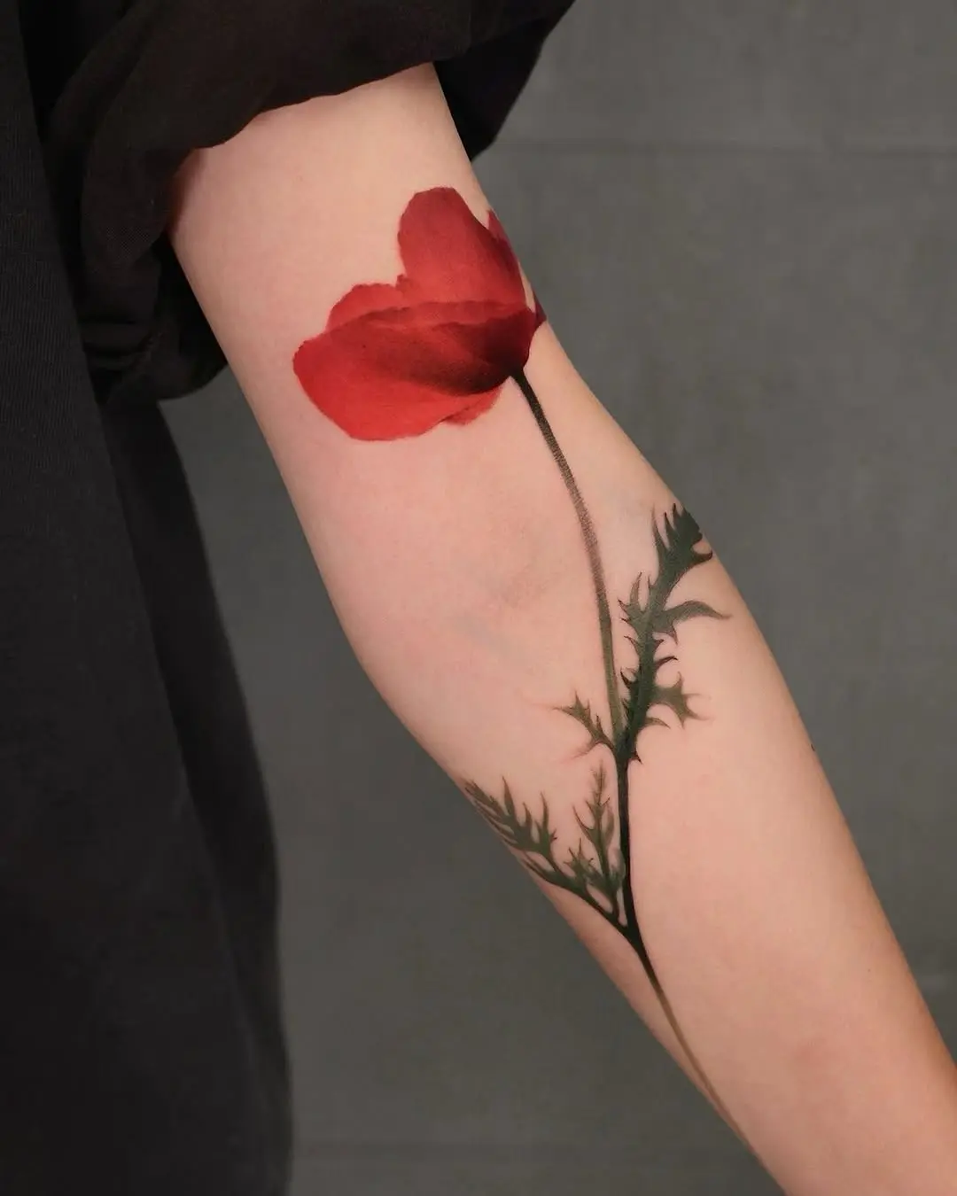 Elegant red poppy tattoo on the arm