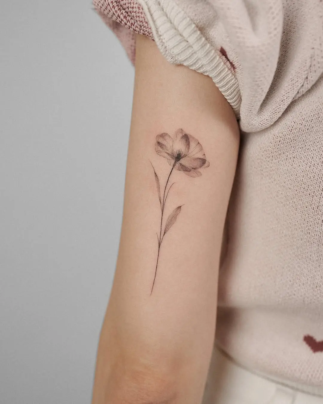 Delicate poppy tattoo showcases minimalist floral art