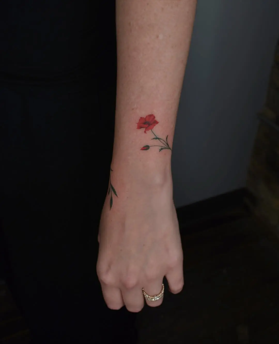 Elegant poppy tattoo on delicate wrist.