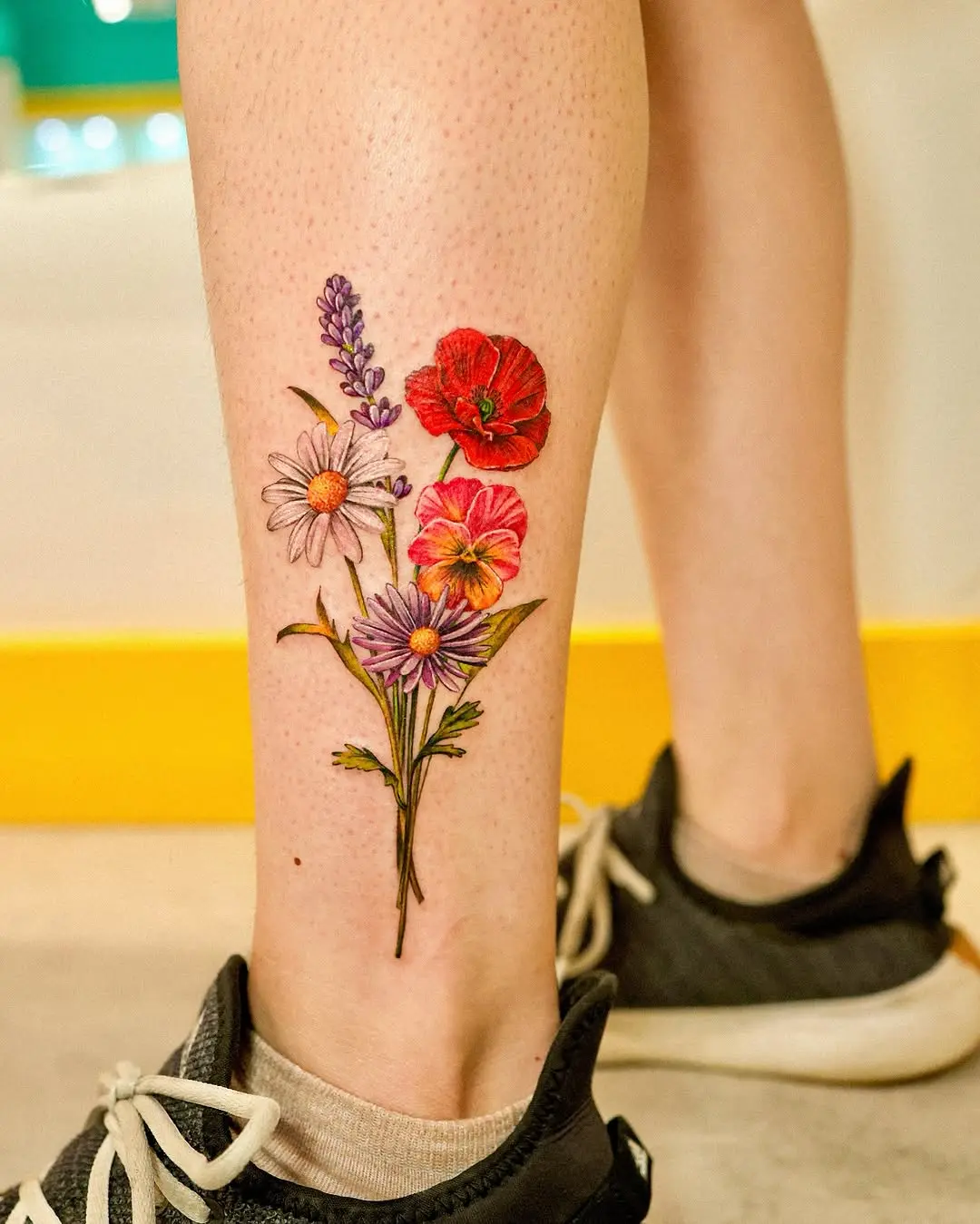 Vibrant floral poppy tattoo on the leg
