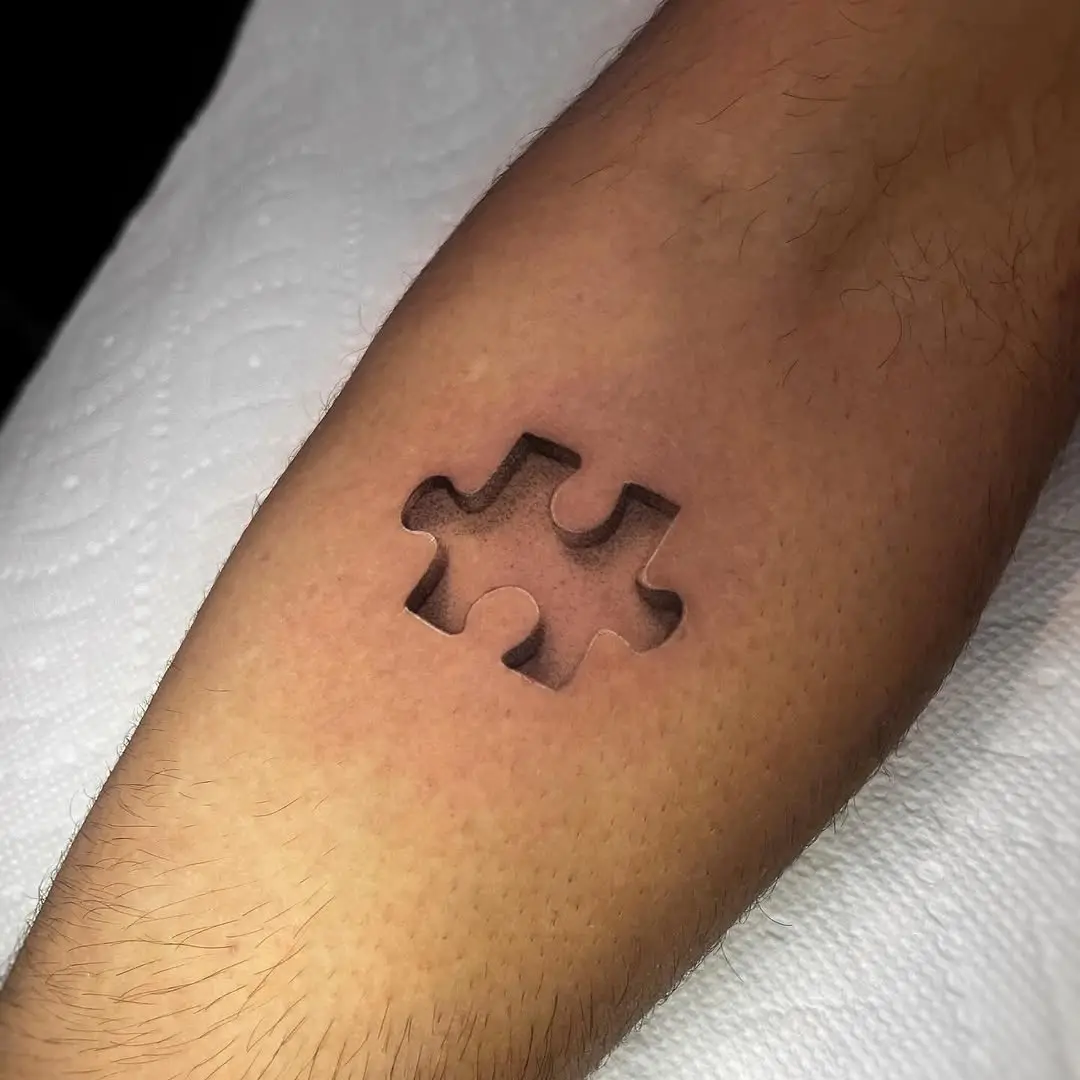 Minimalist puzzle piece tattoo on the arm