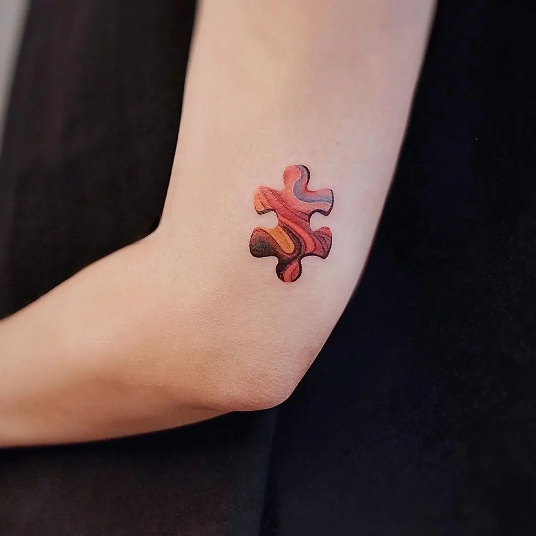 Colorful puzzle piece tattoo on the elbow