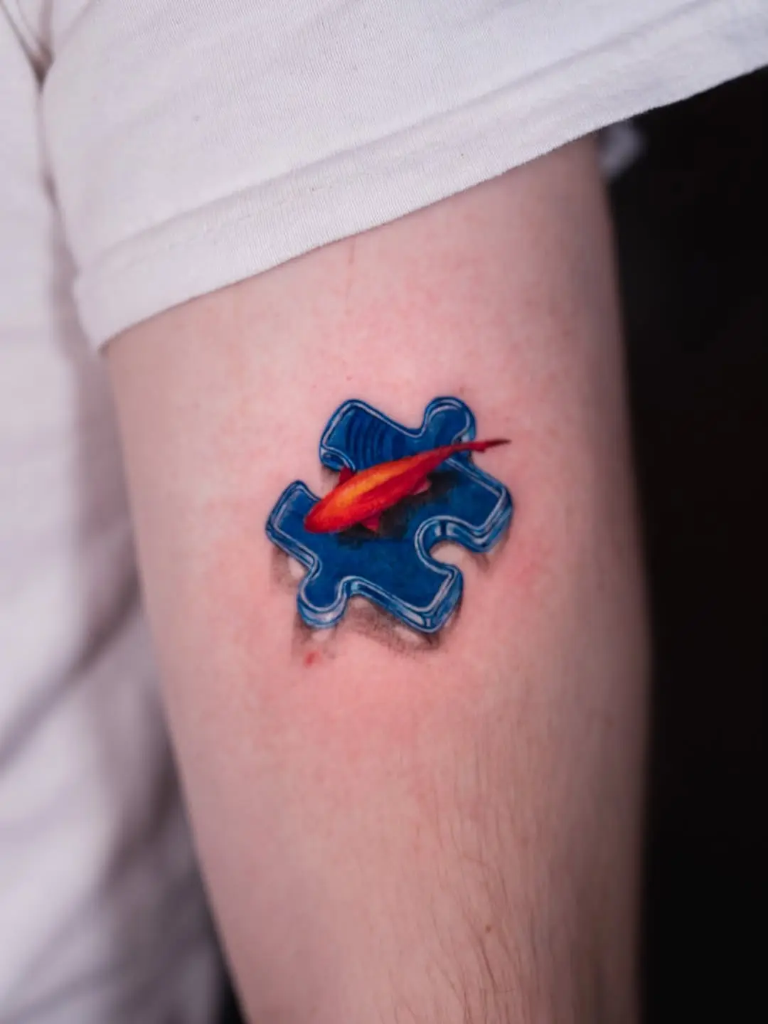 Vibrant goldfish within a puzzle piece tattoo