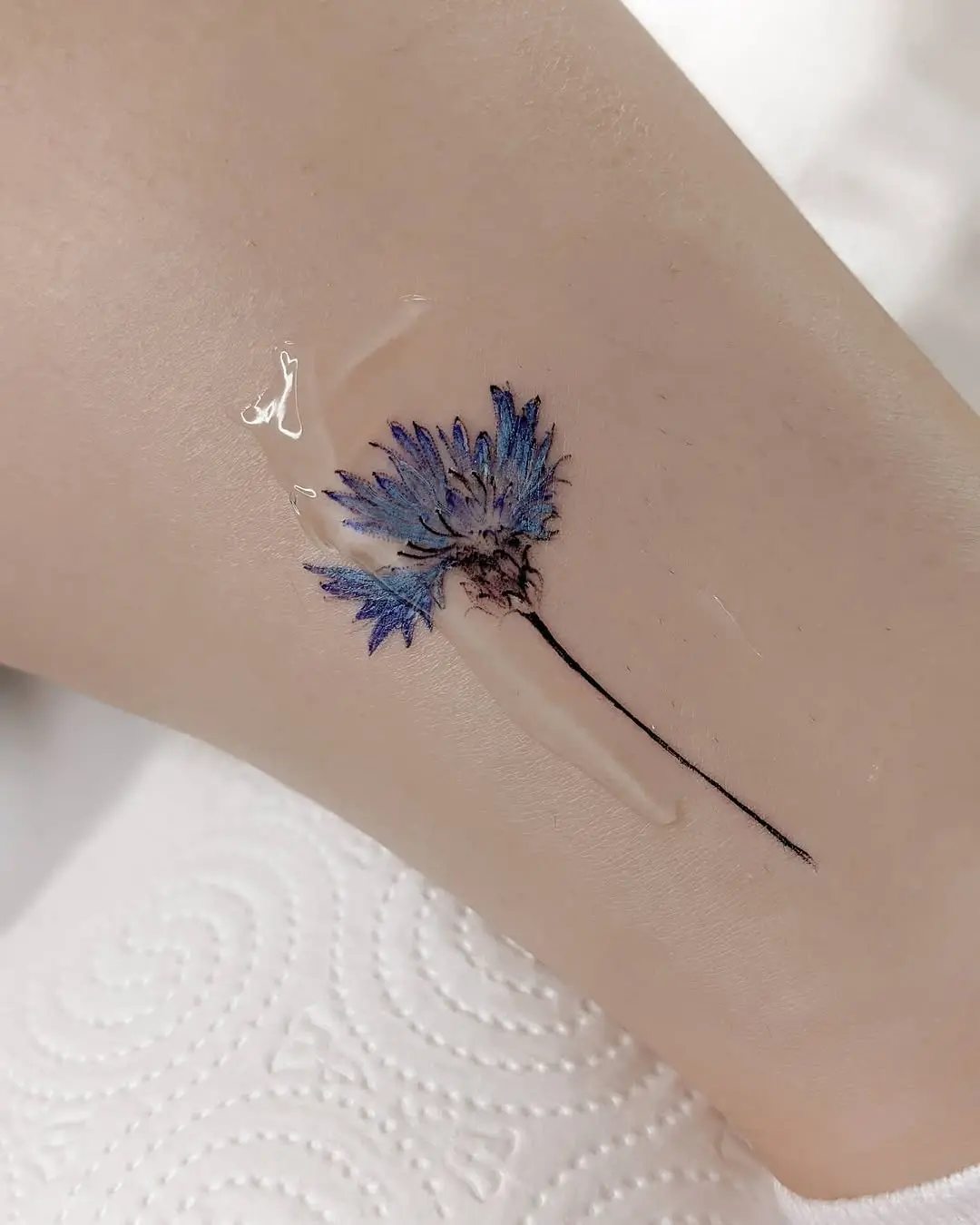 Delicate cornflower tattoo on smooth skin
