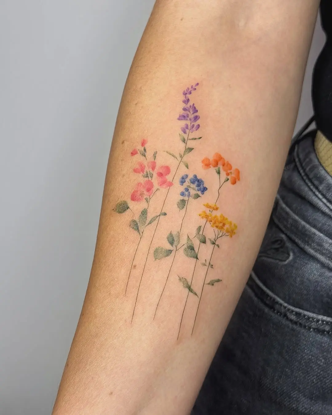 Delicate wildflower tattoo bursting with color