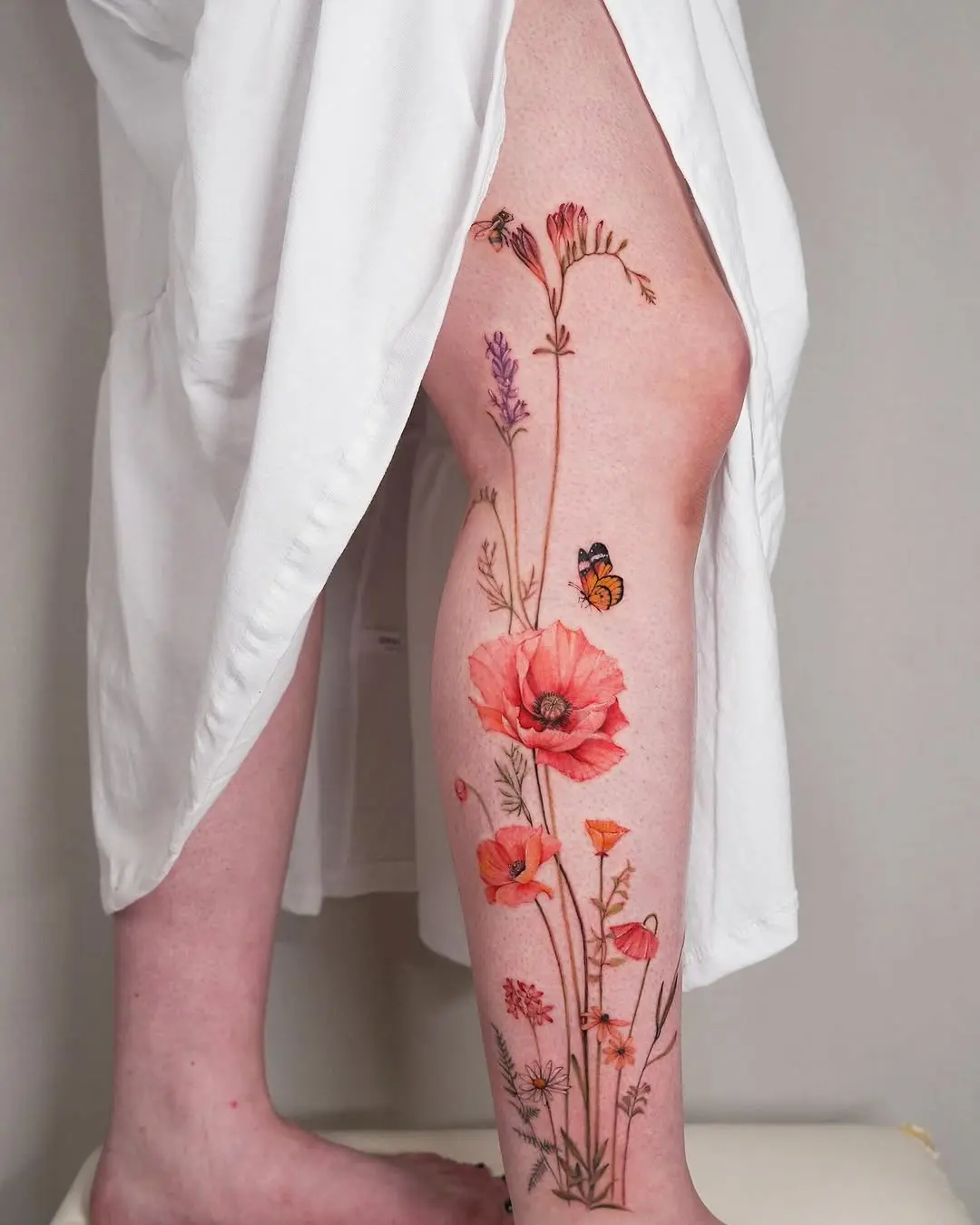 Colorful wildflower tattoo on a leg