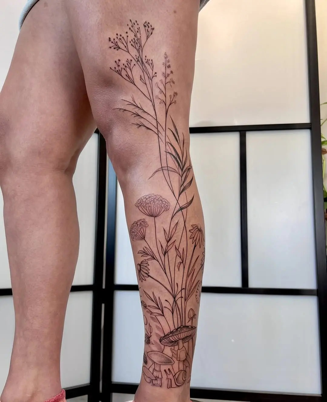 Elegant wildflower tattoo stretching along the leg