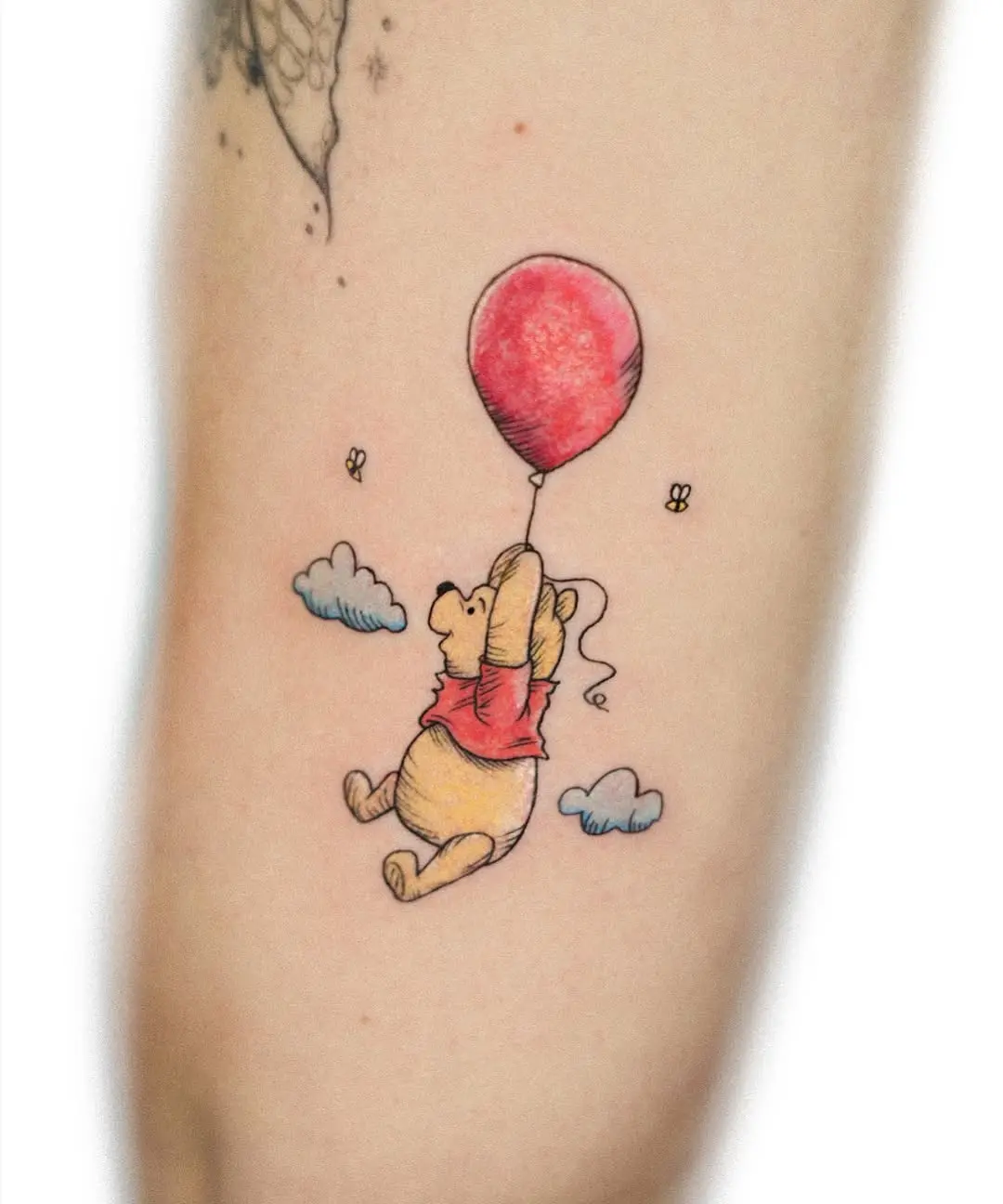 Charming Pooh with a bright red balloon tattoo
