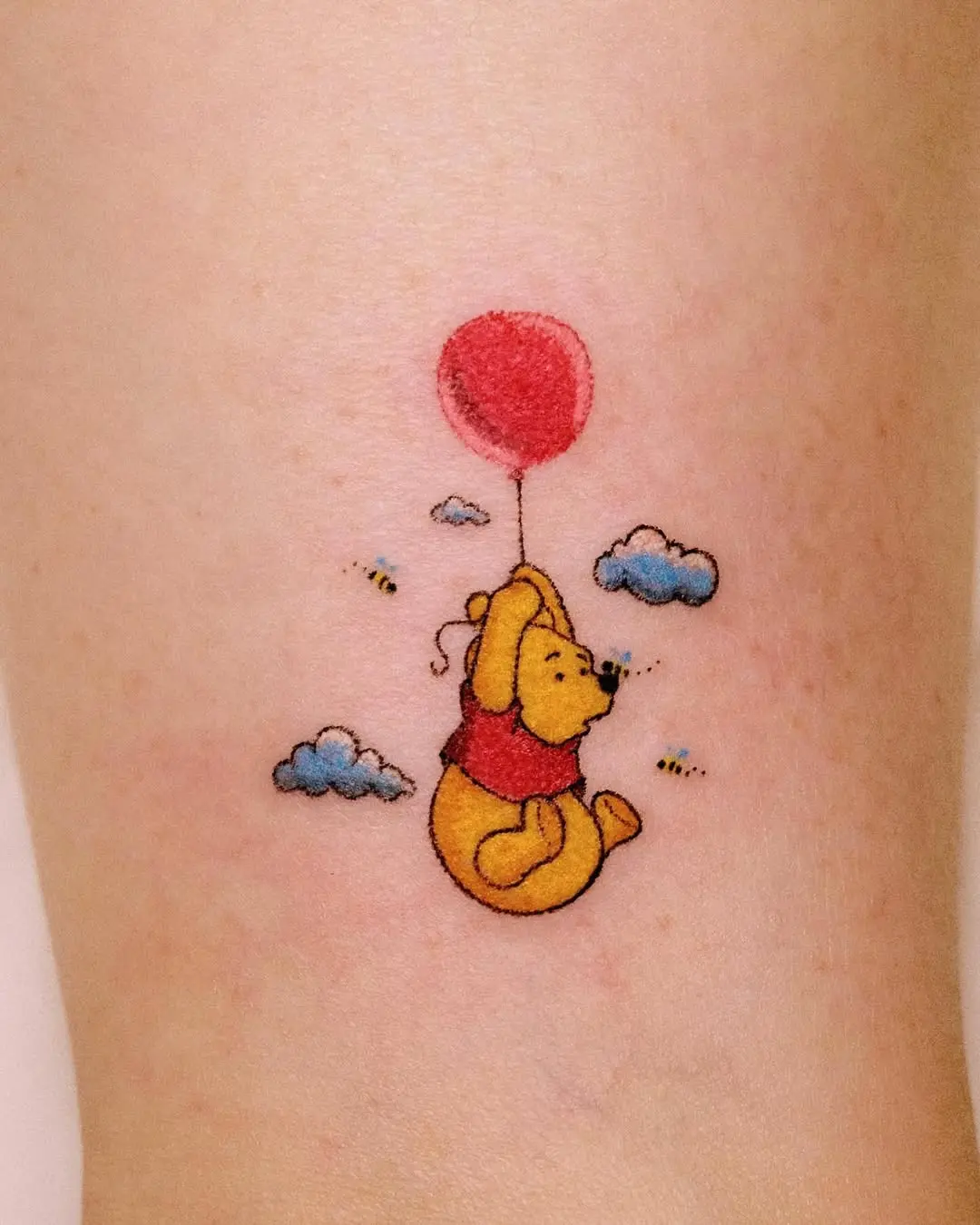 Whimsical Winnie the Pooh with a balloon tattoo