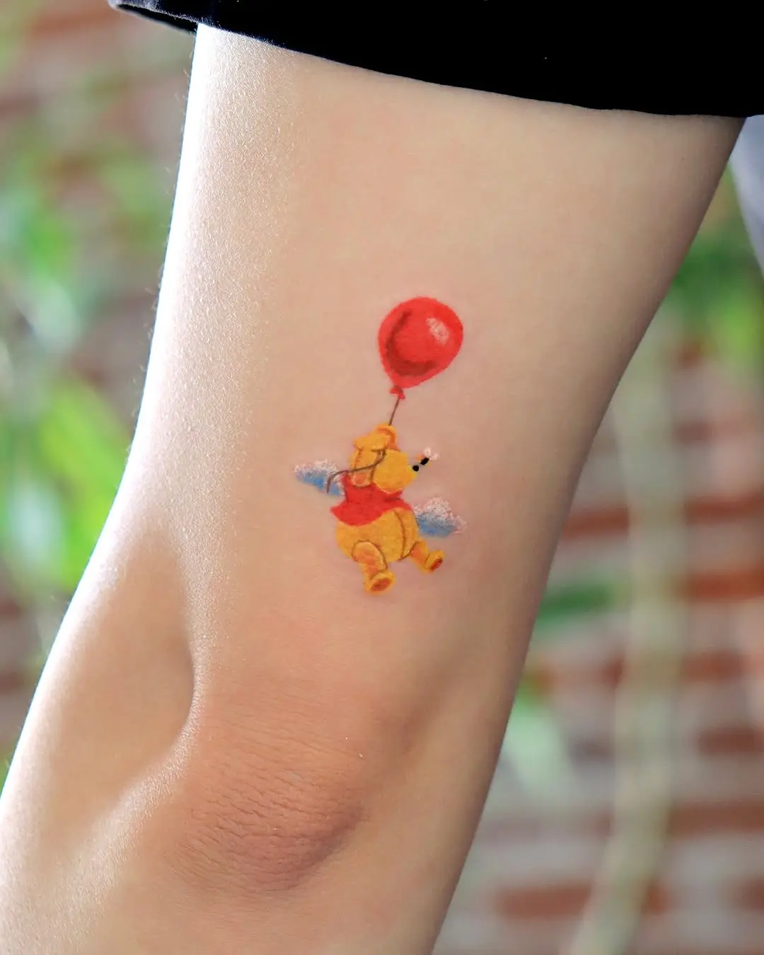 Winnie the Pooh with a red balloon tattoo