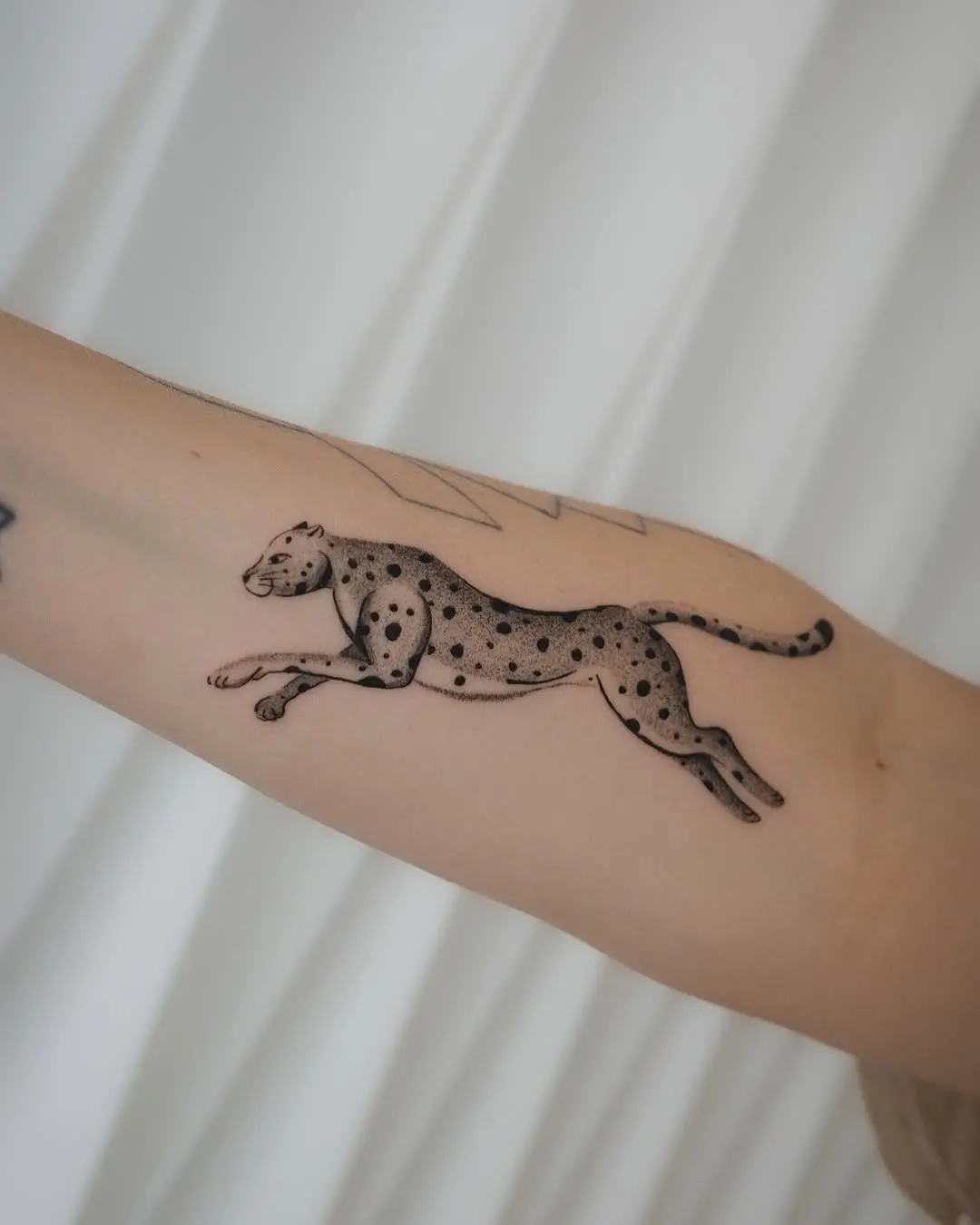 Dynamic leaping cheetah tattoo design on arm