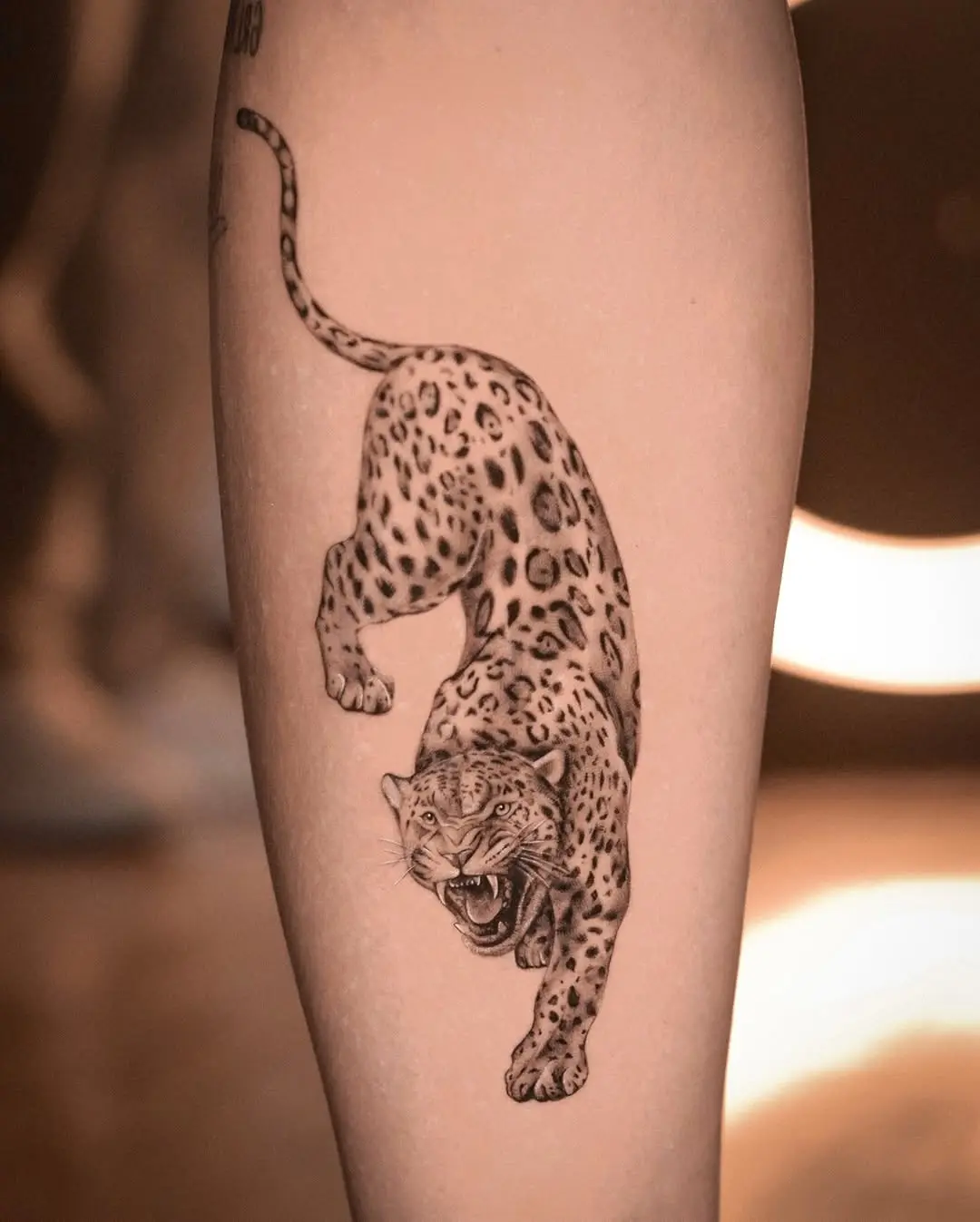 Dramatic leaping cheetah tattoo in black and grey