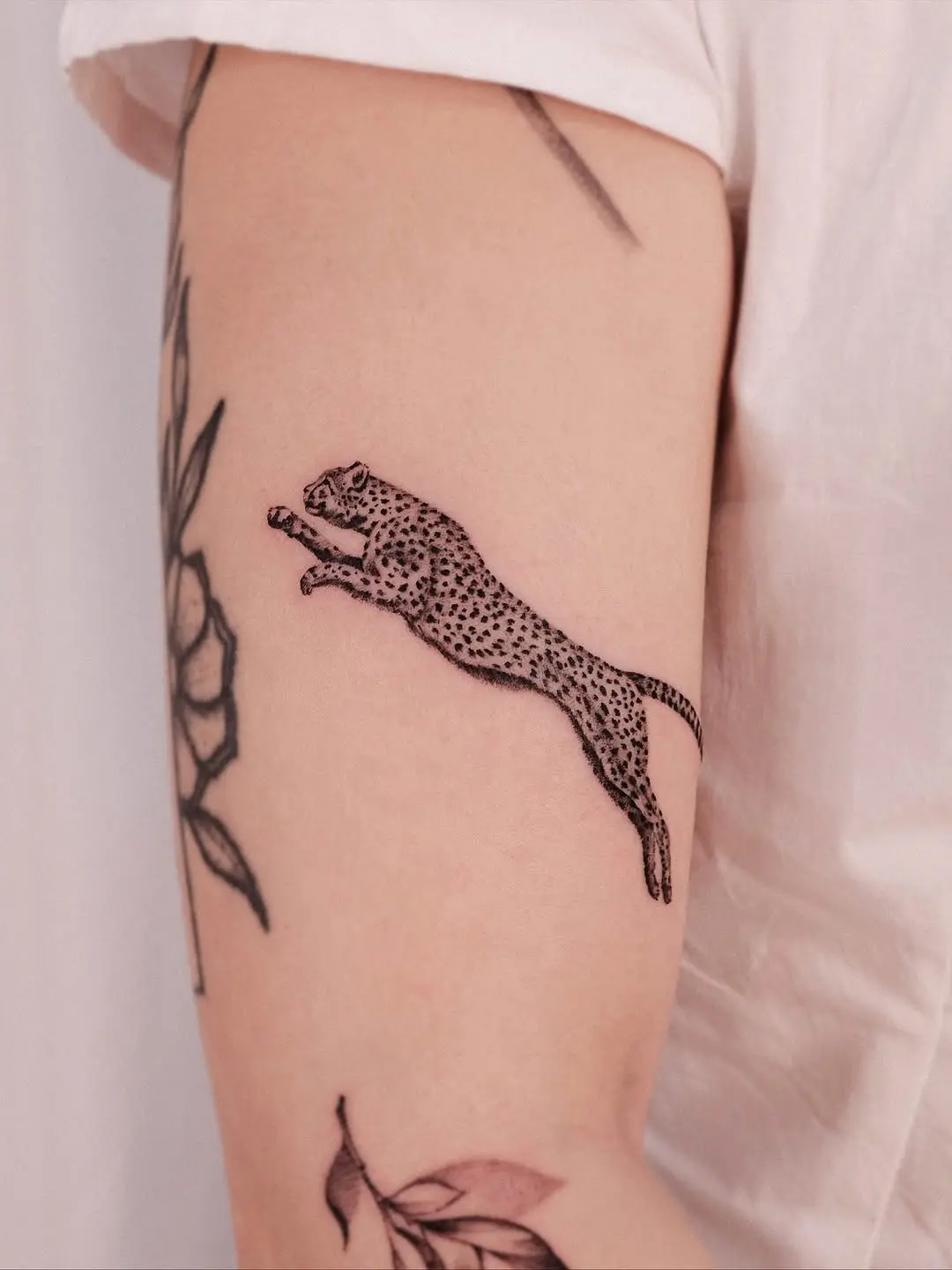 Elegant leaping cheetah tattoo on the arm