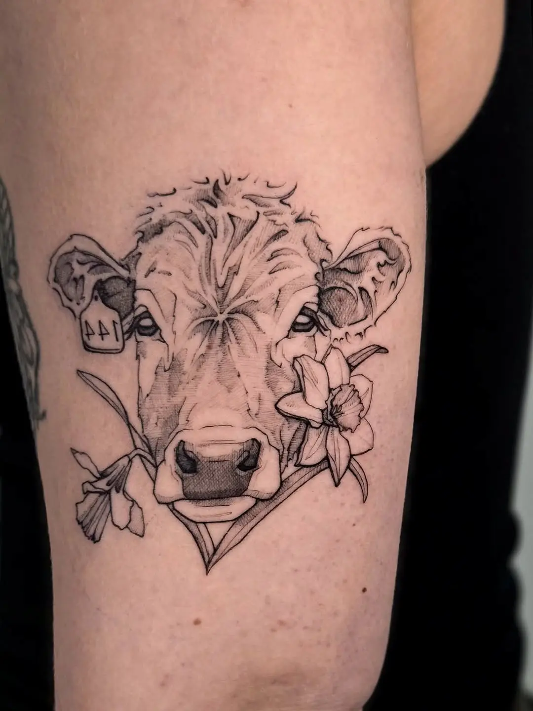 Intricate cow tattoo surrounded by flowers