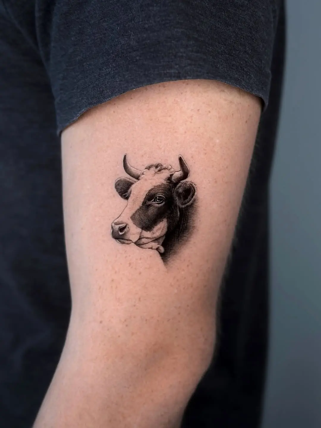 Realistic cow tattoo on upper arm