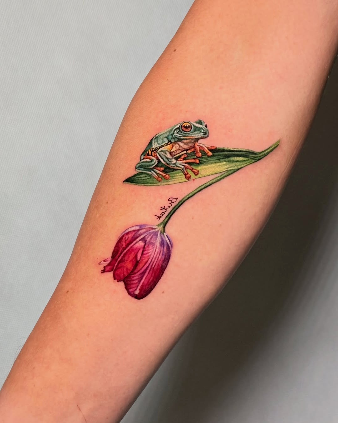Charming frog paired with vibrant tulip tattoo