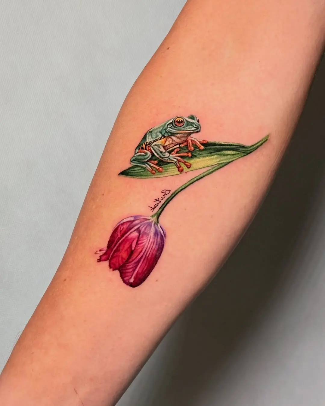 Charming frog paired with vibrant tulip tattoo