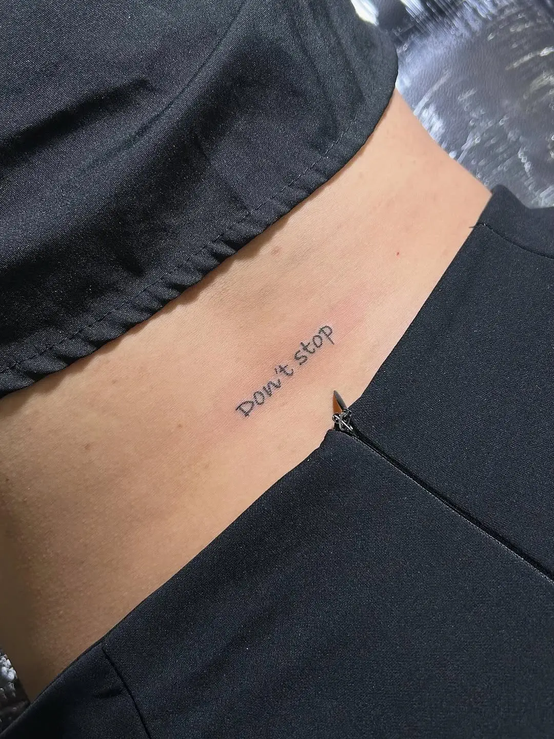 Minimalistic motivational phrase tattoo for lower back