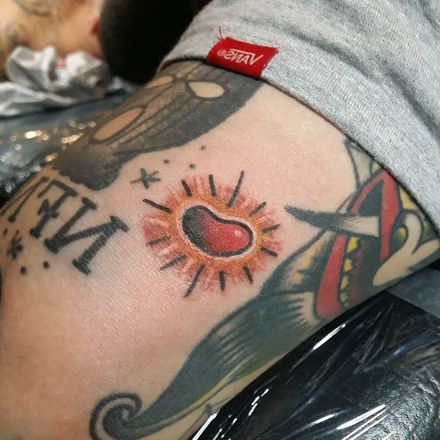 Vibrant jelly bean heart tattoo with sunburst