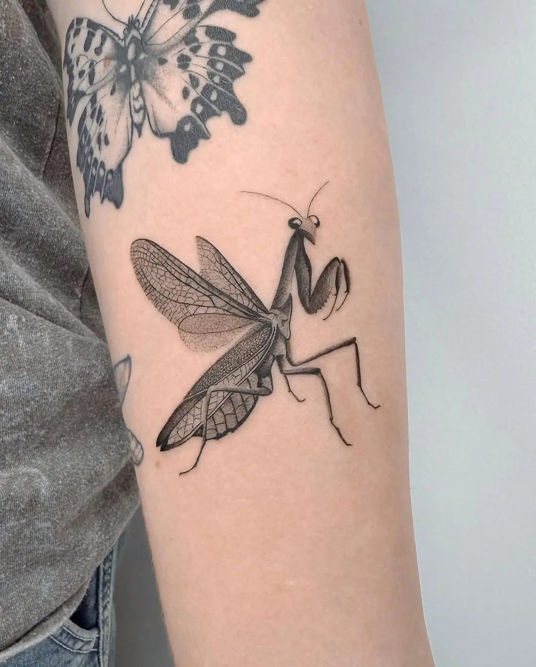 Intricate praying mantis tattoo design on arm