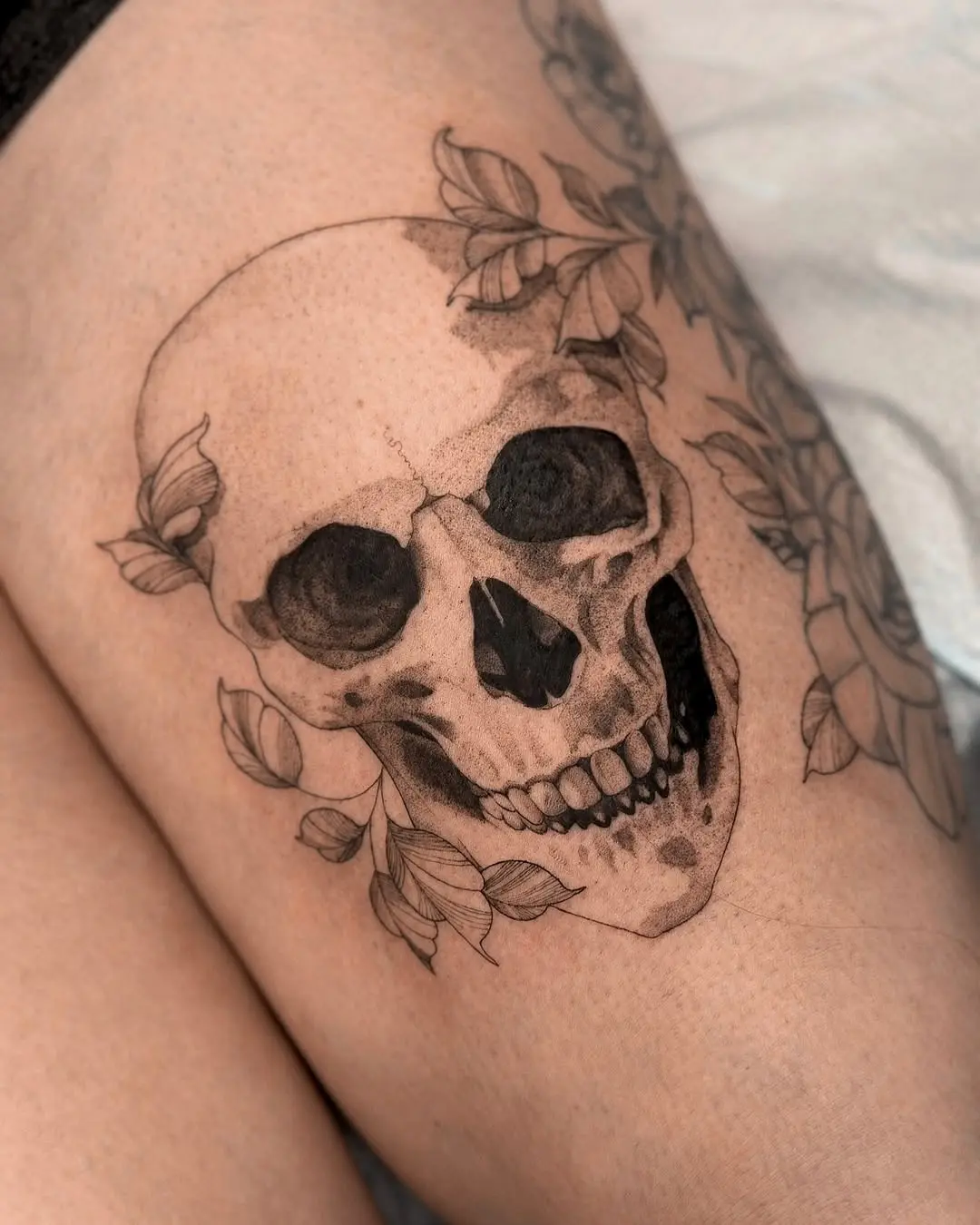 Intricate skull tattoo surrounded by floral elegance