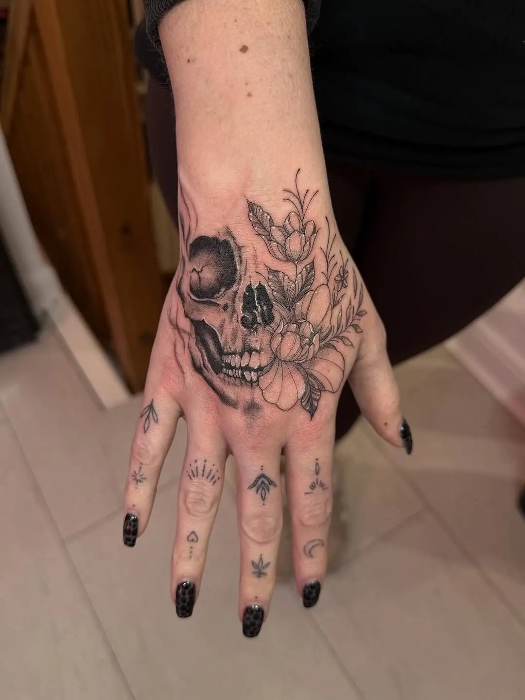 Intricate skull and floral tattoo on hand