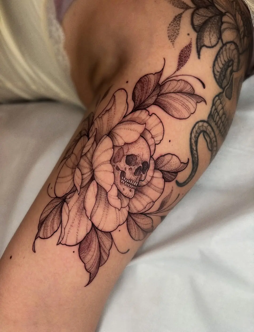 Intricate skull nestled in blooming flower tattoo