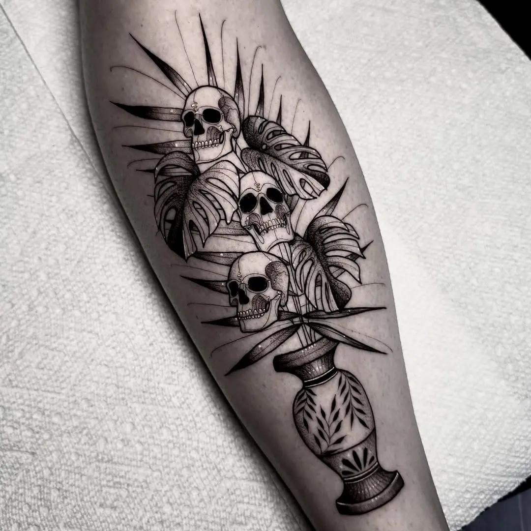 Intricate skull vase tattoo with tropical leaves