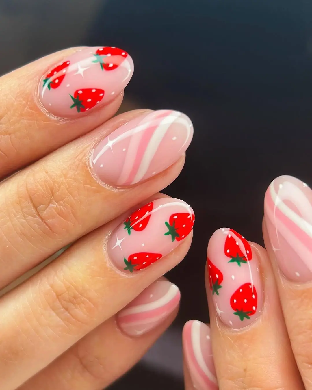 Vibrant strawberry designs on glossy pink nails