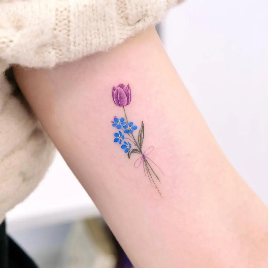 Delicate tulip tattoo with blue flowers accent
