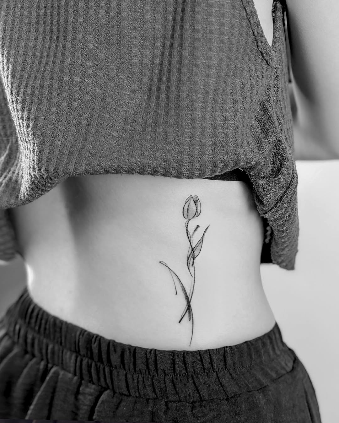Elegant minimalist tulip tattoo on the torso