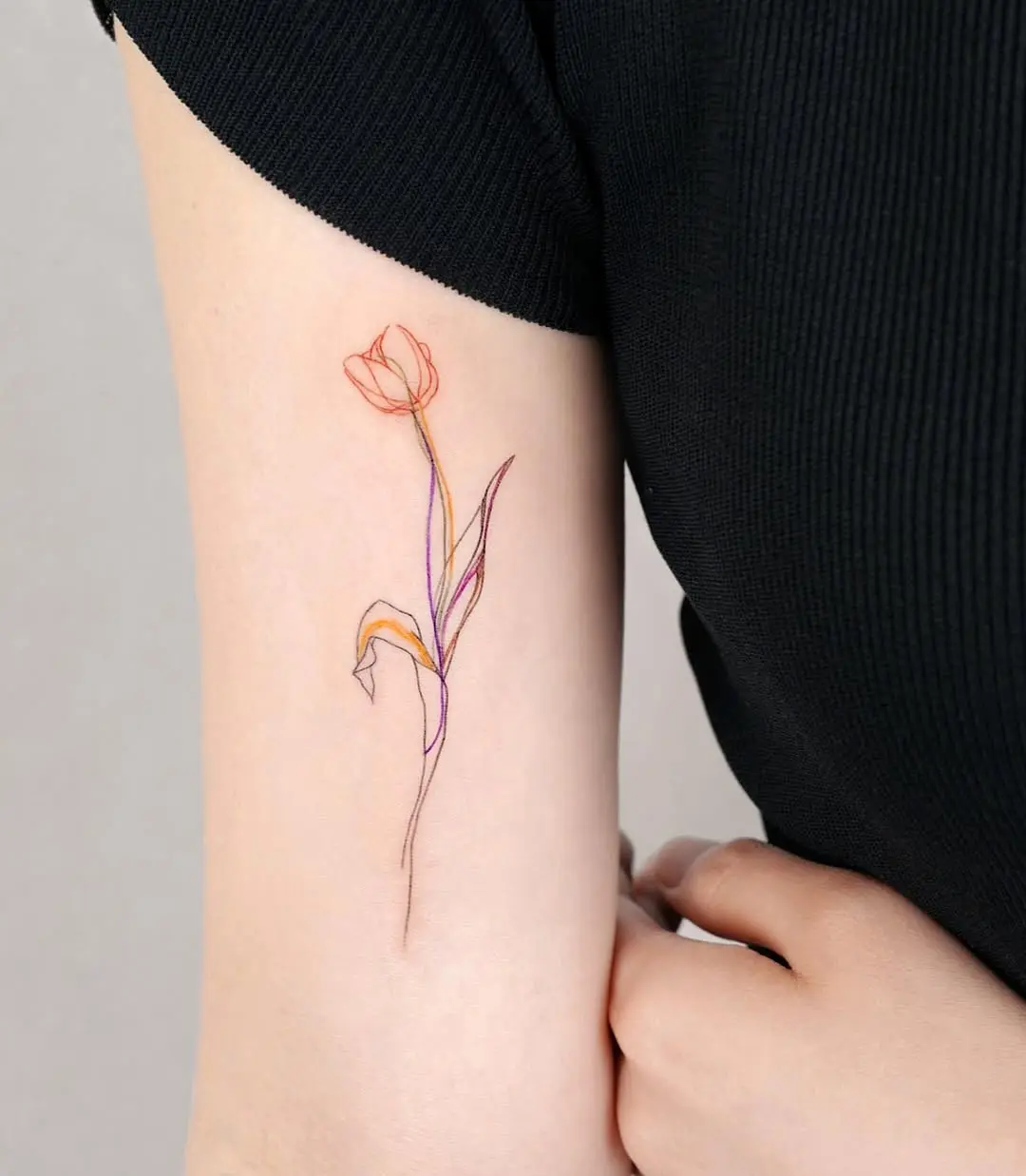 Elegant minimalist tulip tattoo design on arm
