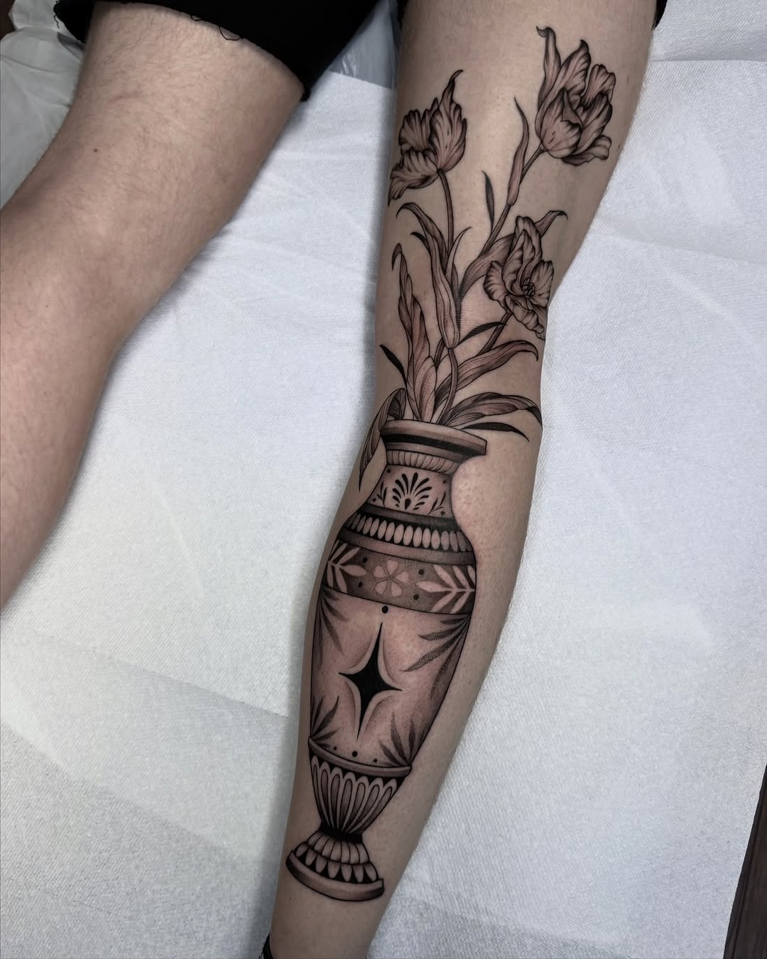 Elegant tulips in an ornate vase tattoo design