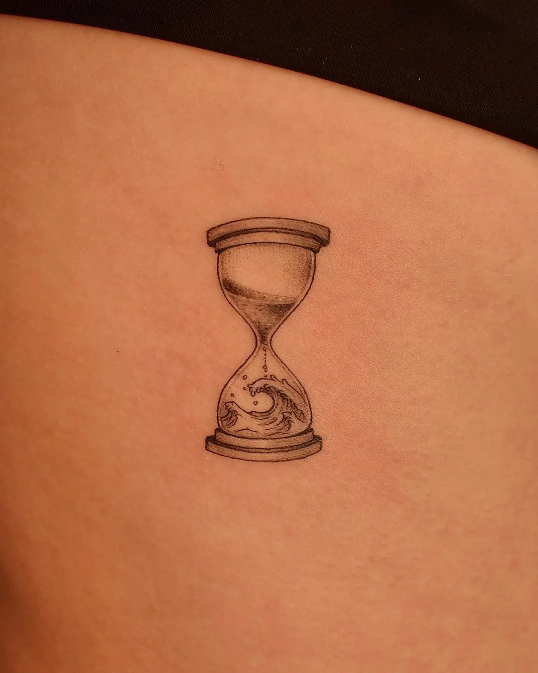 Intricate hourglass tattoo with fish design