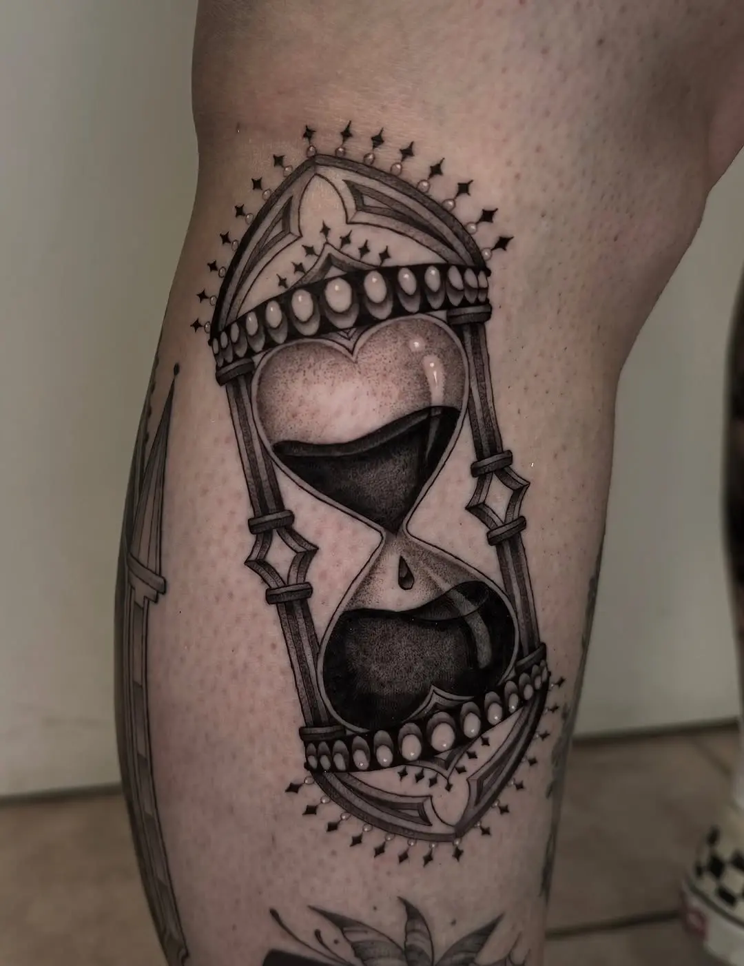 Intricately designed hourglass tattoo with heart shape