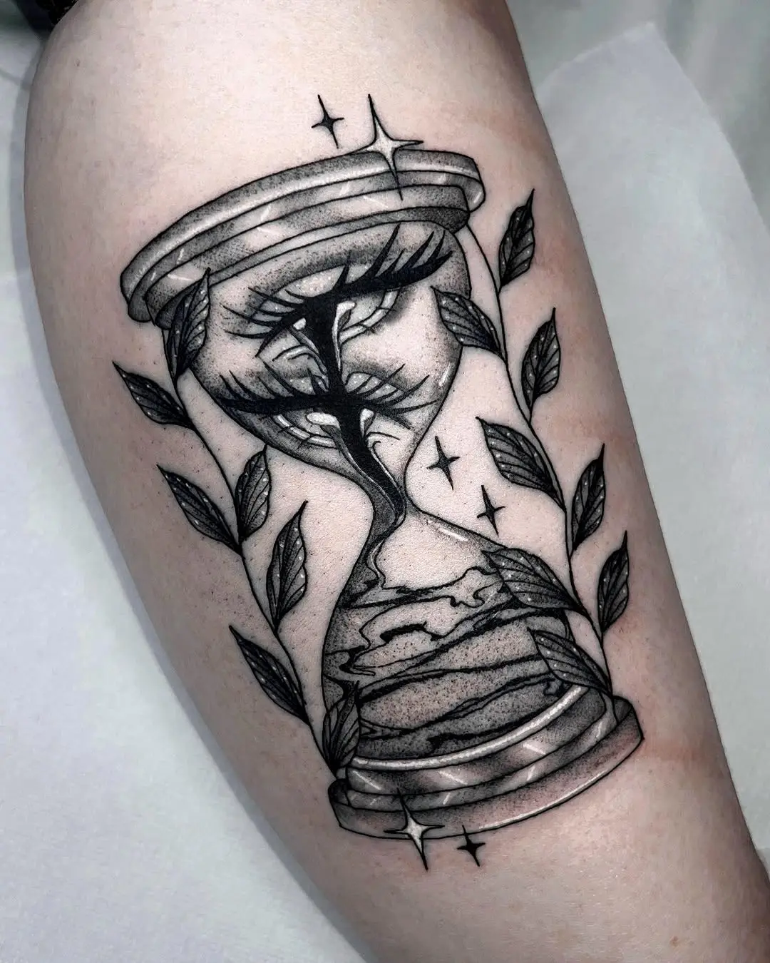 A unique hourglass tattoo featuring nature's elements