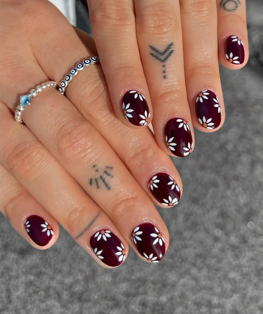 Charming daisy nail design on burgundy base