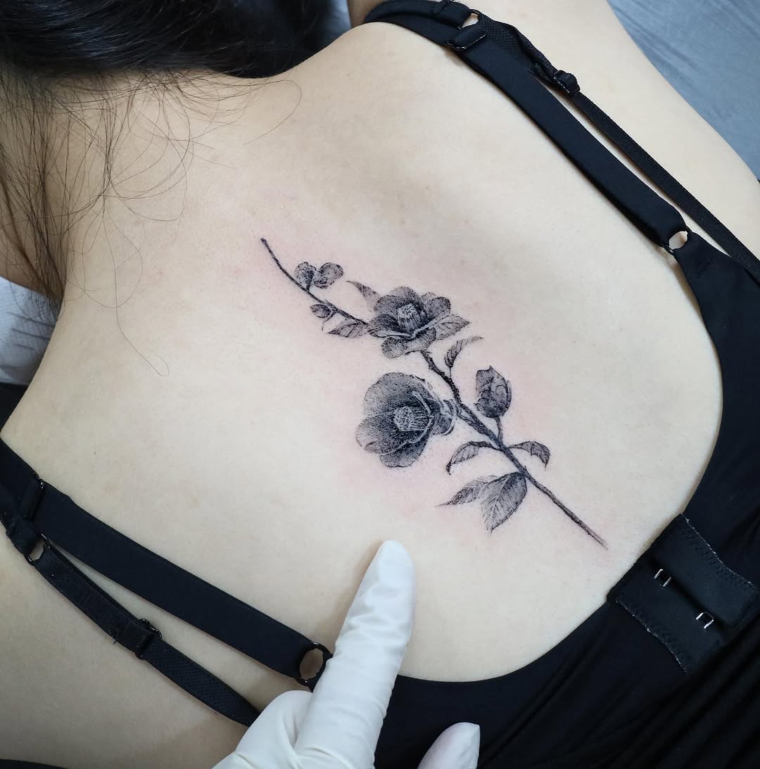 Elegant camellia tattoo on shoulder blade