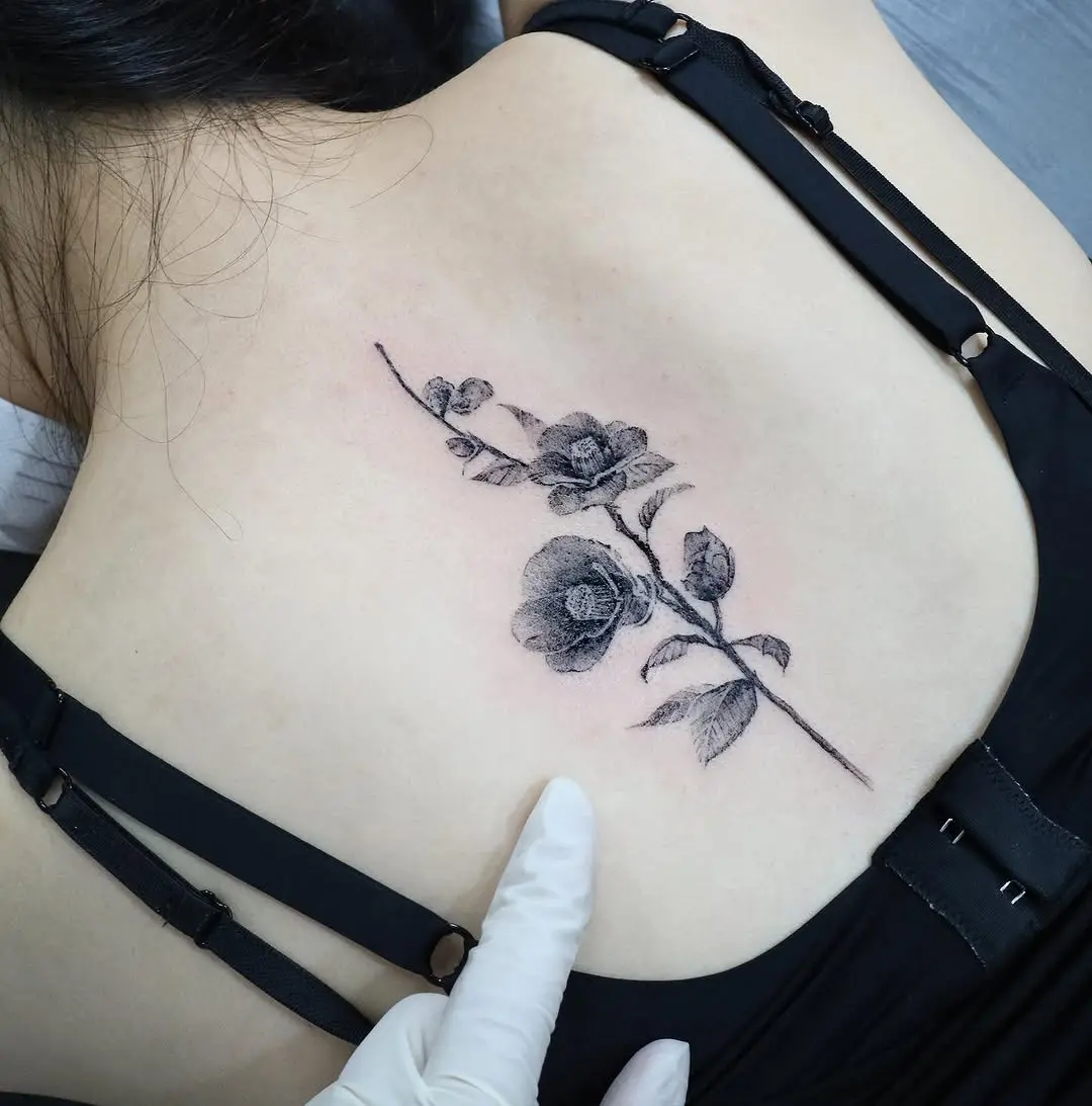 Elegant camellia tattoo on shoulder blade