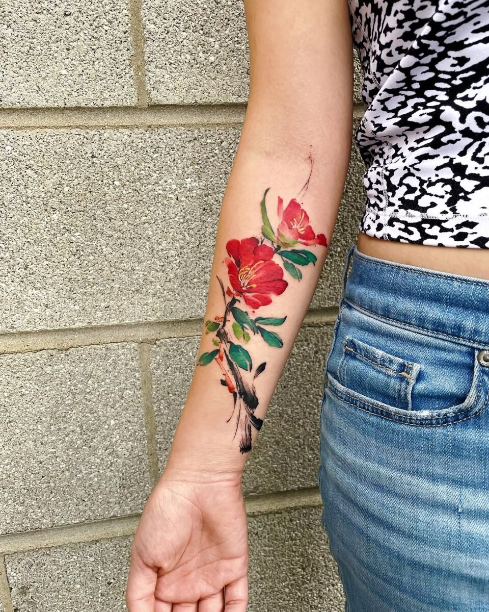 Vibrant camellia tattoo design on forearm