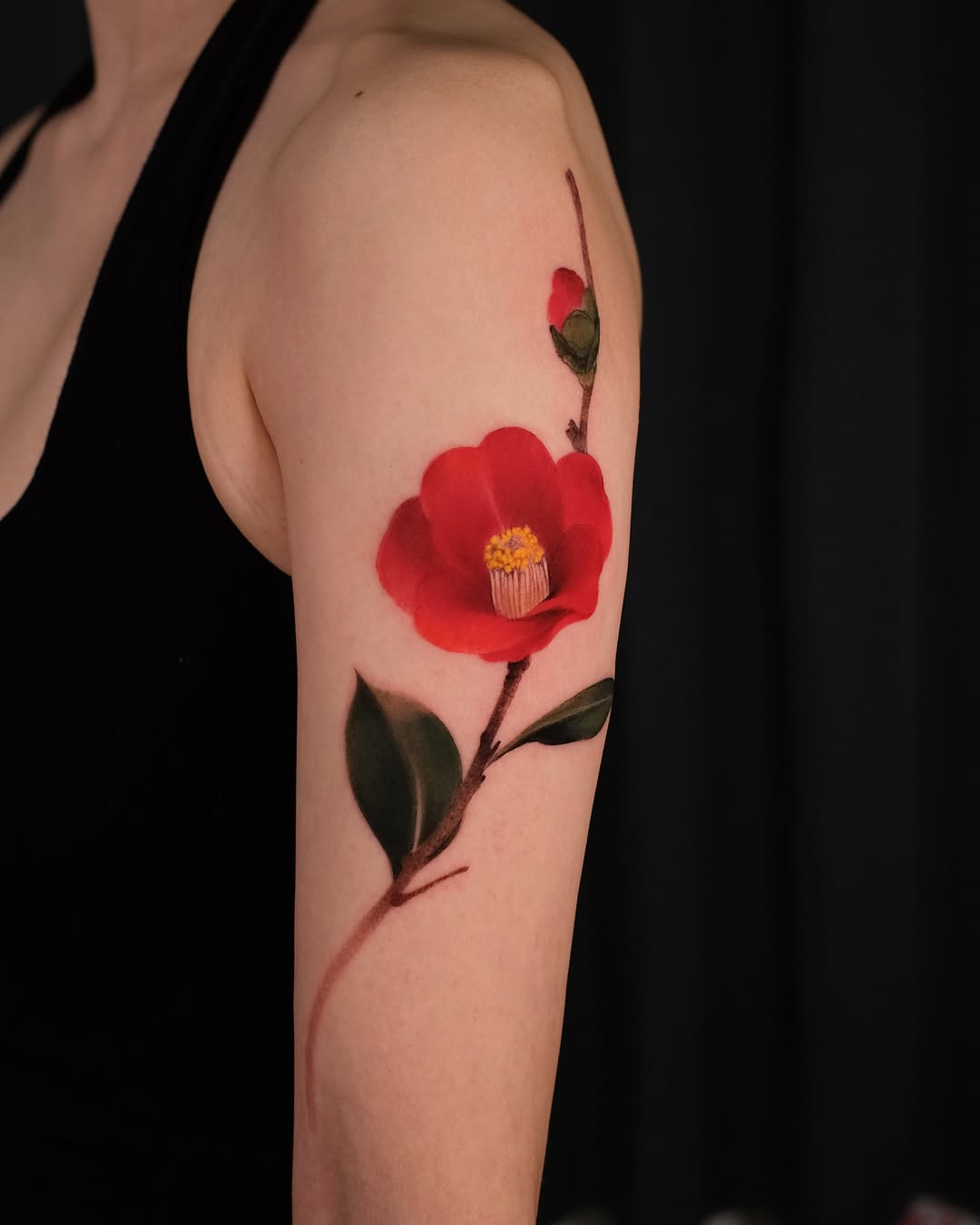 Vibrant red camellia tattoo on the arm