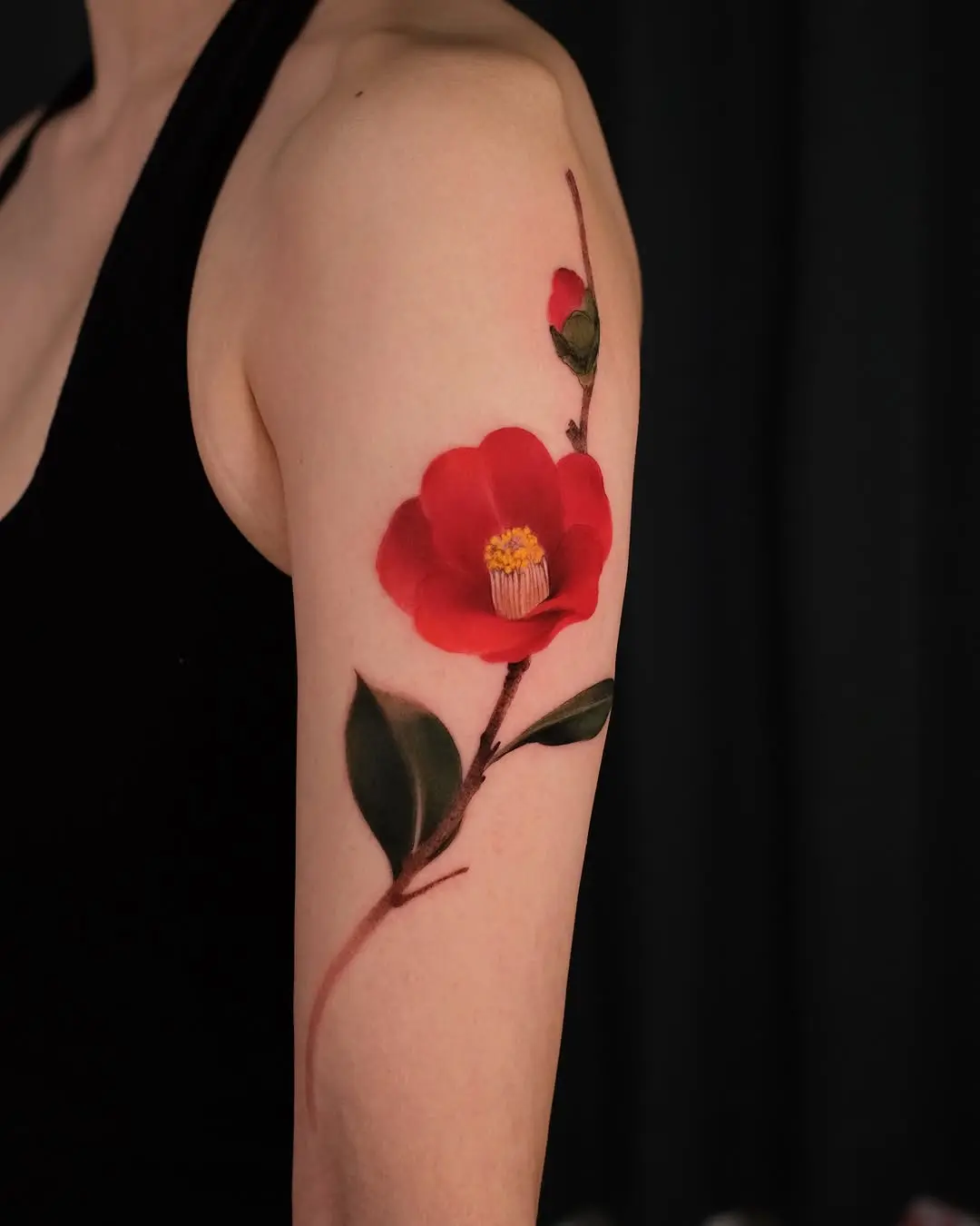 Vibrant red camellia tattoo on the arm