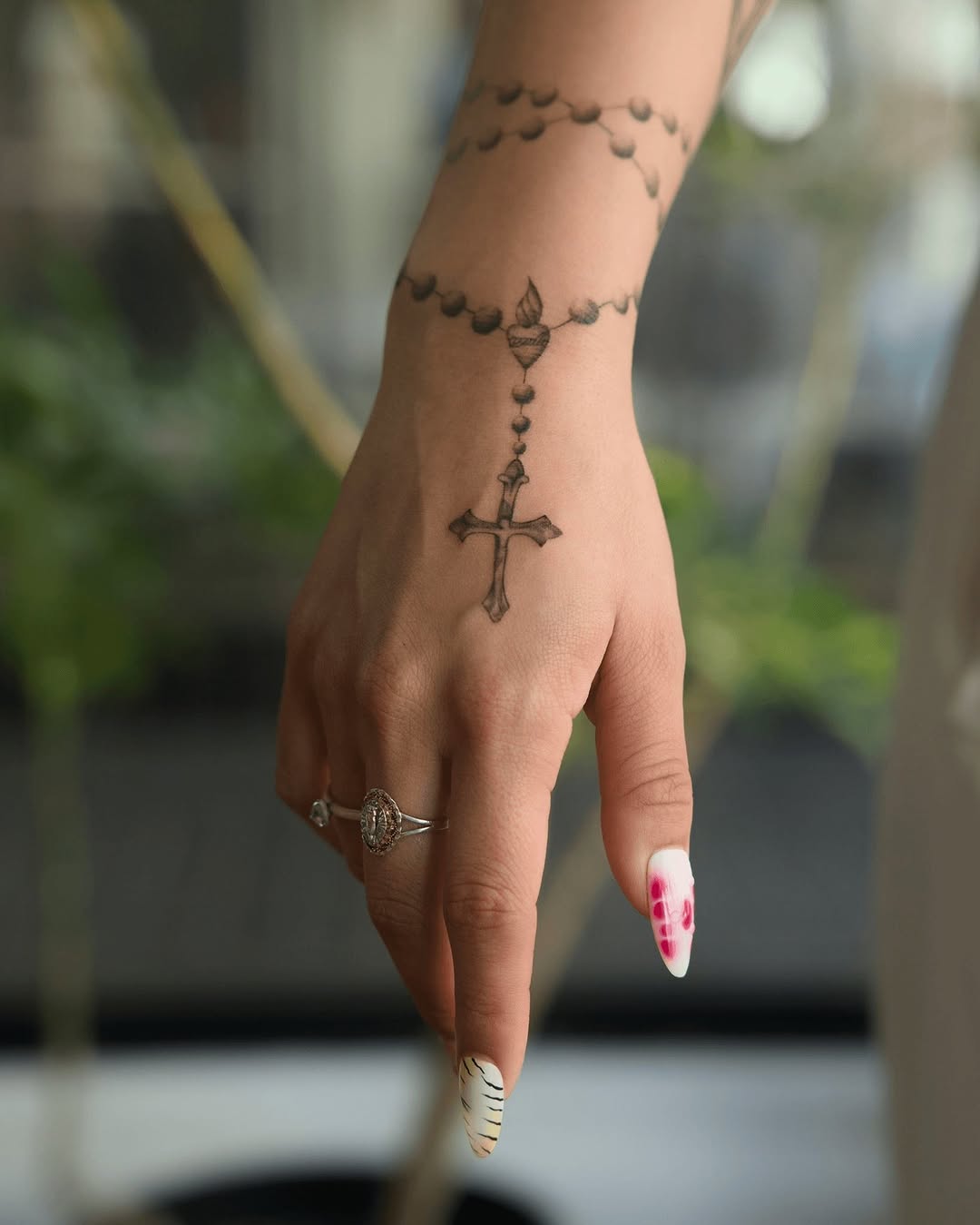 Rosary-inspired cross tattoo on a hand