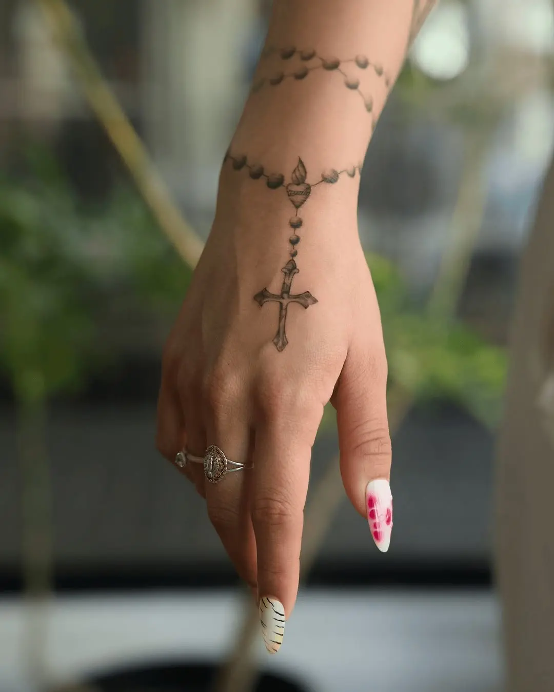 Rosary-inspired cross tattoo on a hand
